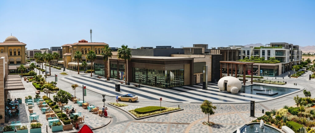 A modern outdoor shopping plaza with palm trees, cafe seating, and storefronts, the type of small business Business Owners Policy Florida protects.