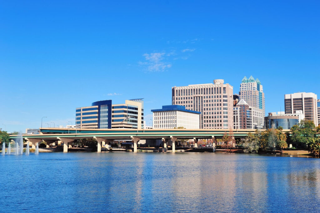 A downtown Orlando skyline with office towers reflected in a lake, framed by a bridge, the type of property Commercial Property Insurance protects.