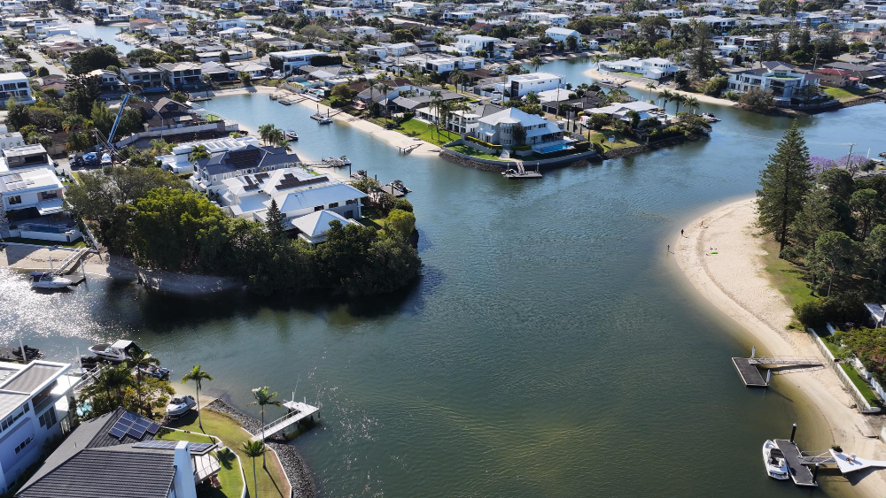 Aerial view of a canal-front neighborhood with homes, docks, and boats surrounding calm waterways, properties suited to Flood Insurance.