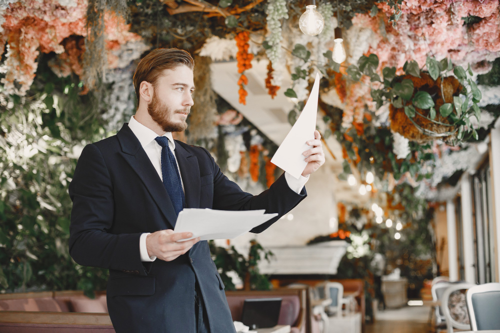 An event planner reviewing paperwork inside a venue decorated with florals and string lights, preparing for Special Event Liability Insurance Florida.