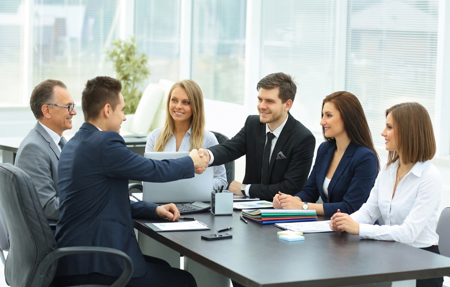 A group of business professionals shaking hands across a conference table during a meeting, finalizing a Specialty Liability Coverage Florida agreement.