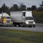 Two commercial trucks driving on a Florida highway at dusk, illustrating a 3A Allied Insurance blog article on commercial vehicle coverage risks