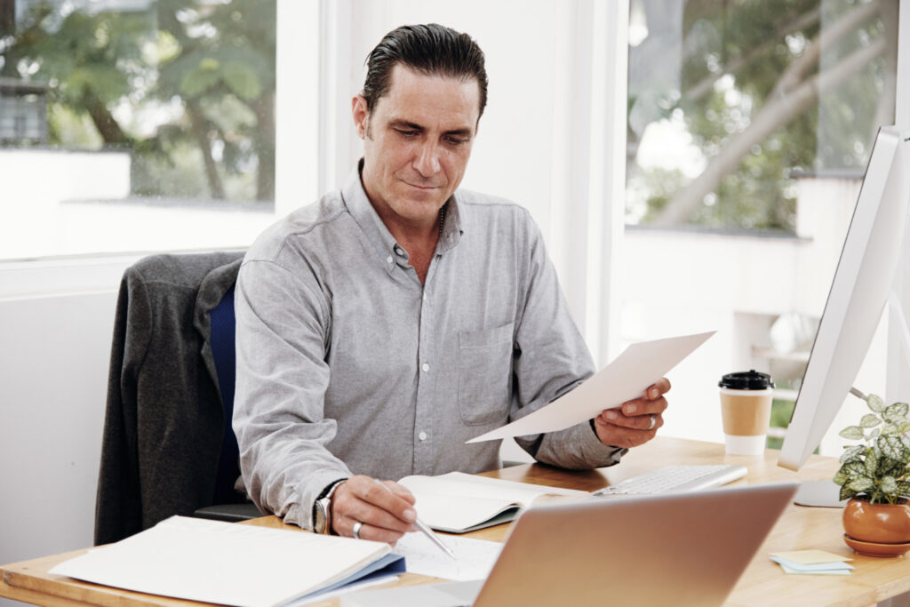 Businessman reviewing paperwork at his office desk, illustrating a 3A Allied Insurance blog article on liability protection for Florida businesses