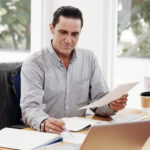 Businessman reviewing paperwork at his office desk, illustrating a 3A Allied Insurance blog article on liability protection for Florida businesses