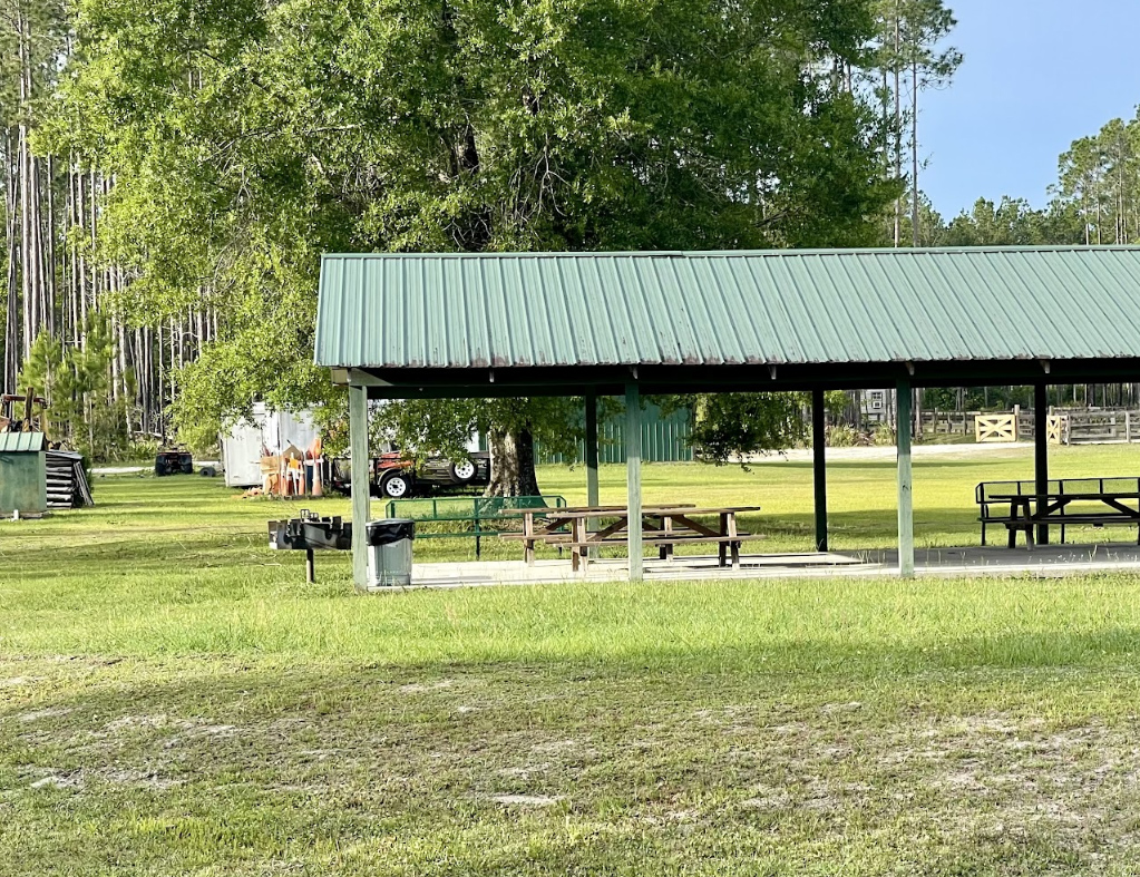 Baker Insurance coverage area image of a rural picnic pavilion with farm equipment and open green grounds surrounded by trees in Baker County, Florida.