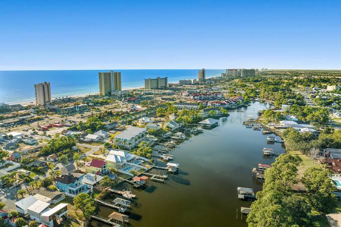 Aerial view of Bay Insurance coverage area showing a coastal waterway, boat docks, and Panama City Beach's high-rise skyline along the Gulf shoreline.