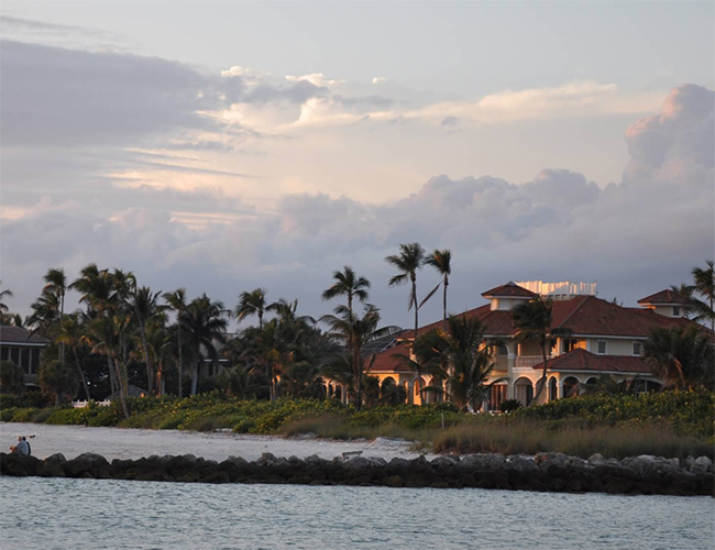 Collier County Insurance coverage area image of a coastal estate with palm trees and a rock jetty at sunset near Naples, Florida.
