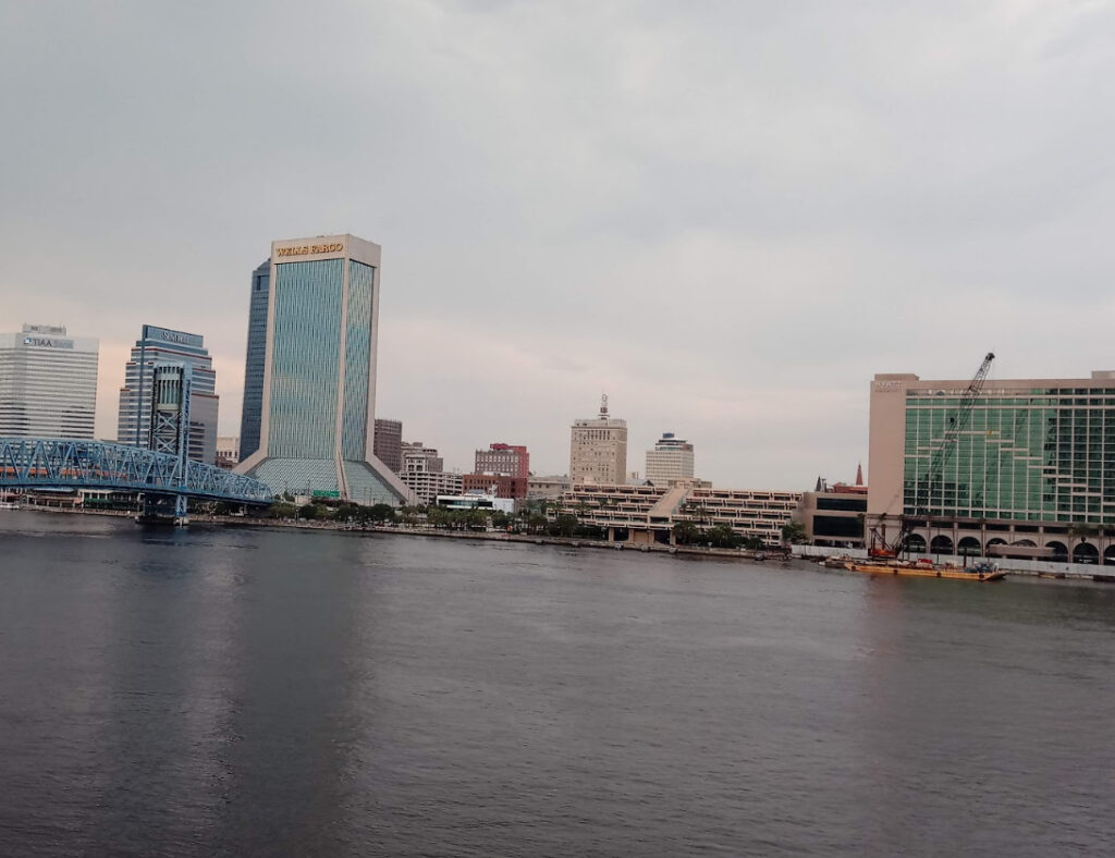 Jacksonville skyline along the St. Johns River with downtown high-rises and a working bridge, reflecting the port and urban risk Duval Insurance covers.