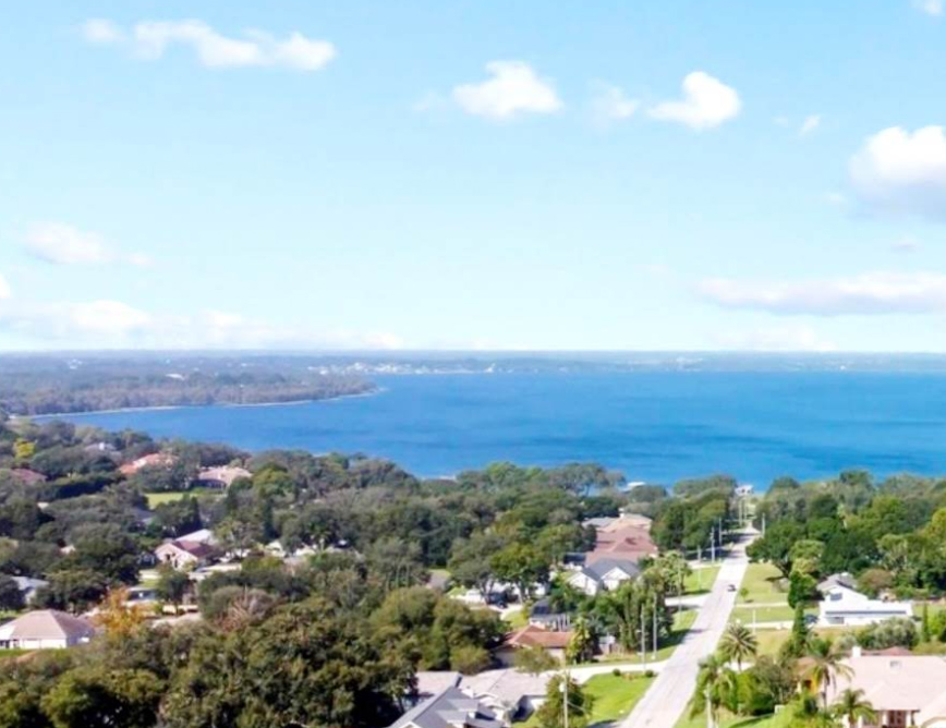 A lake surrounded by rooftops and green neighborhoods in Lake County, the lakefront property 3A Allied Insurance protects with Lake County Insurance.