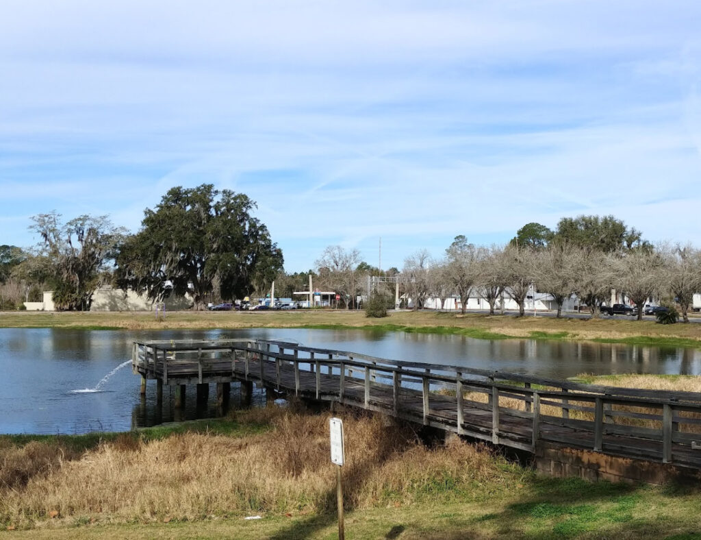 A wooden pond boardwalk beside farmland and oak trees in Madison County, the rural community 3A Allied Insurance protects with Madison County Insurance.