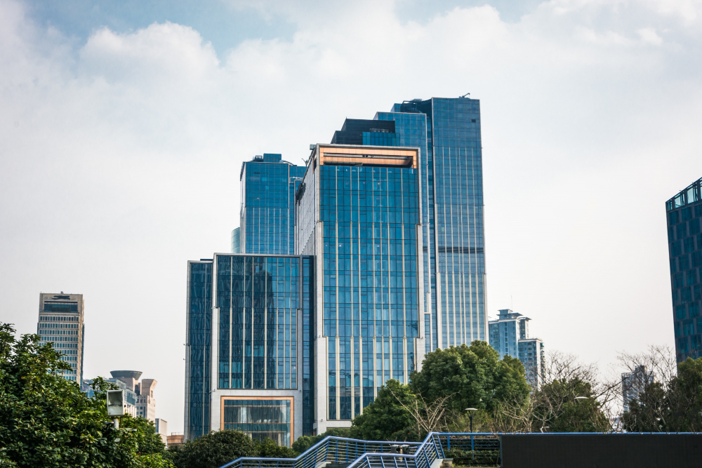 Blue glass office skyscrapers rising above a city skyline with trees in the foreground, representing business insurance coverage for Florida companies