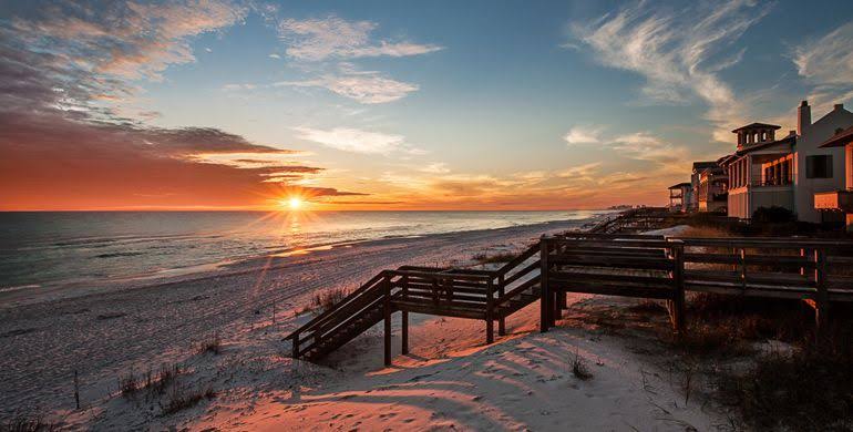 A sunset view of a Santa Rosa County beach with boardwalk stairs and homes, the storm risk 3A Allied Insurance covers with Santa Rosa County Insurance.