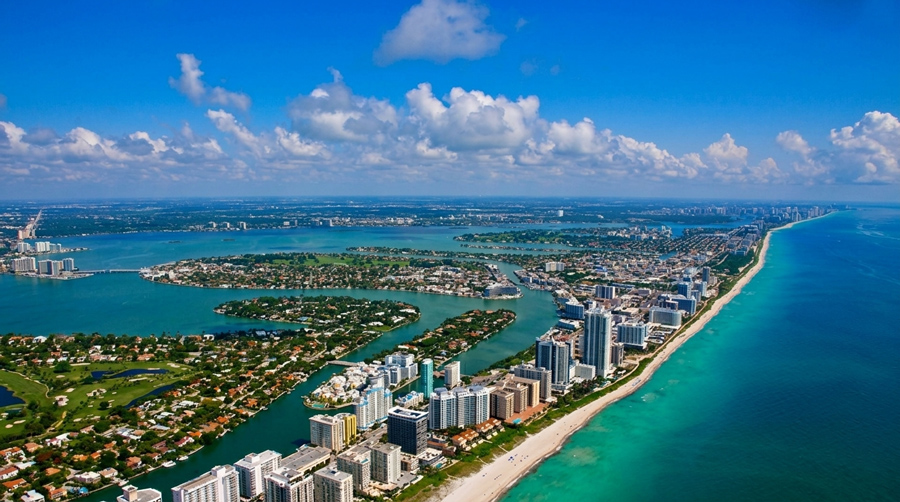 An aerial view of Miami Beach shows dense waterfront high-rises along turquoise water, representing the South Florida Insurance coverage 3A Allied provides.
